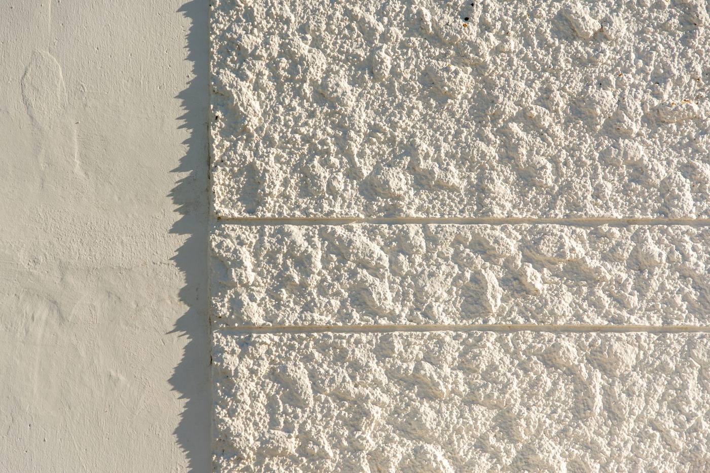 Weiß verputzte Fassade mit Fugenschnitt im Streiflicht