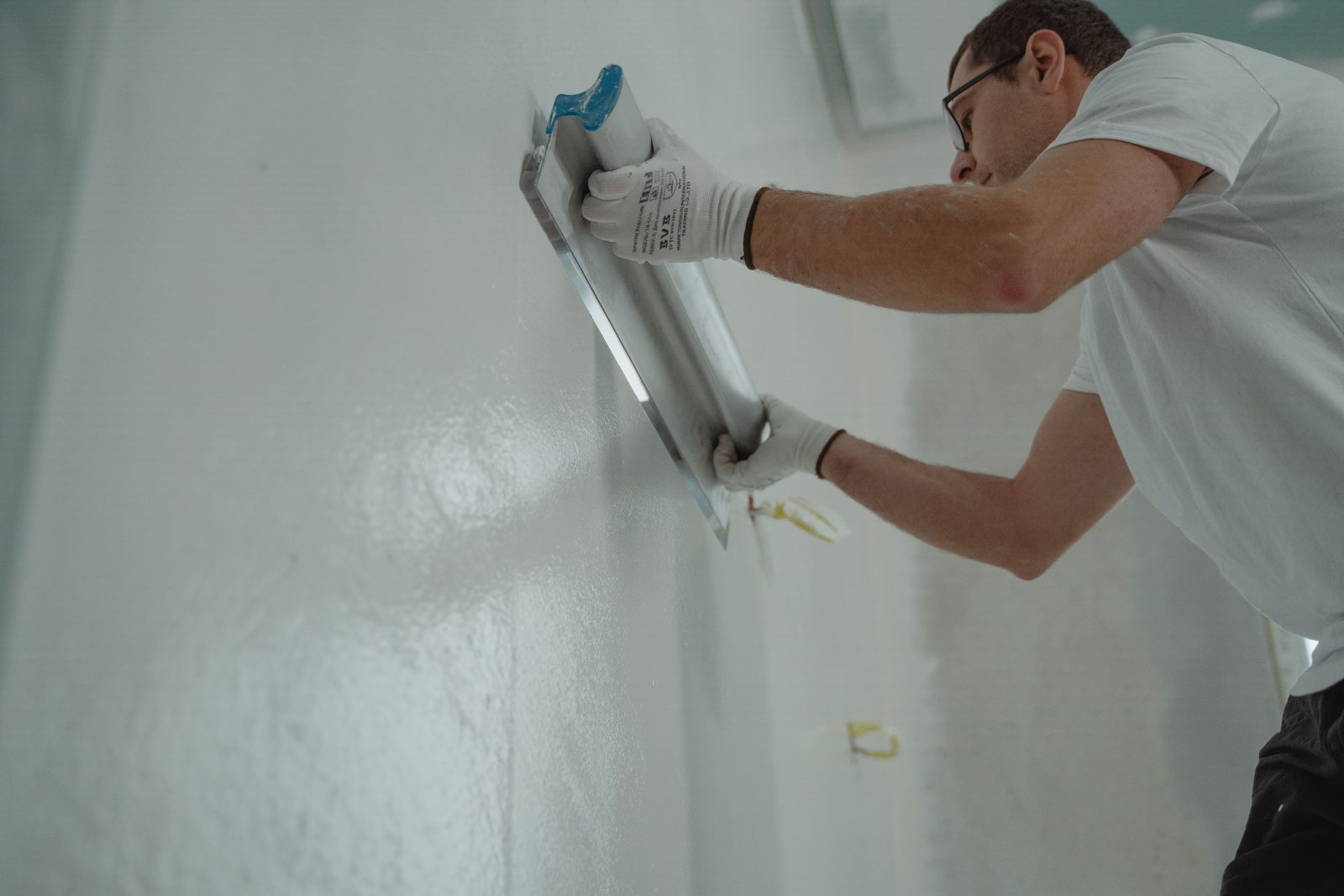 Handwerker zieht Glattputz mit der Glättkelle an einer Innenwand ab